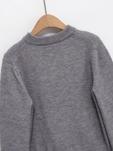 Detailed view of grey crew neck cardigan texture with wood hanger and fine knit fabric