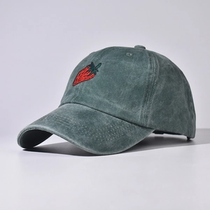 Dettaglio del ricamo a fragola sulla trama del cappello da baseball verde lavato