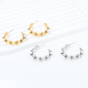 Detailed view of C-shaped stainless steel earrings with daisy flowers in gold and silver