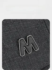 Detailed macro view of dark grey woven fabric featuring a metallic silver letter M logo