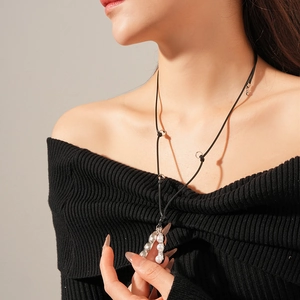 Détail du collier pendentif cosse de pois avec perles et cordon noir sur modèle