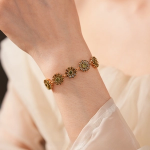 Detailed macro view of gold plated bracelet with olive green floral zircon stones