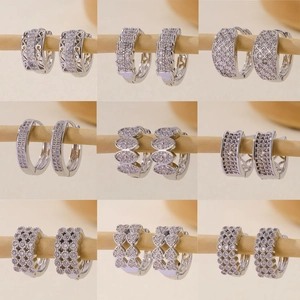 Set of nine silver zircon hoop earrings in various elegant patterns on wooden displays