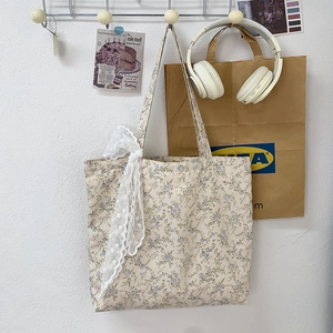 Detailed close-up of a floral canvas tote bag featuring white lace trim on the shoulder strap