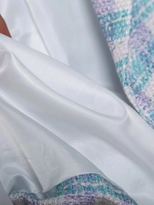 Detail of premium purple and mint tweed fabric with smooth white satin lining