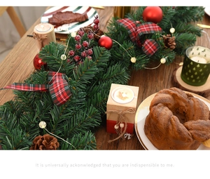 Christmas garland with red ornaments, plaid bows, and pinecones on a cozy wooden table