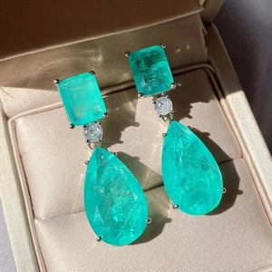 Pear-cut emerald green gemstone earrings with rectangular studs in a jewelry box