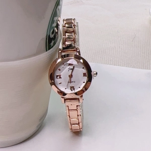 Close-up of rose gold vintage quartz watch with white mother of pearl dial and metal strap
