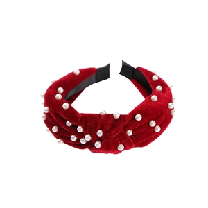 Close-up of red velvet knotted headband with white pearls on a white background