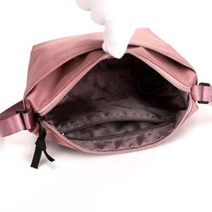 Pink nylon dumpling bag showing internal compartments and logo lining in a main view