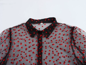 Close-up of black mesh shirt with red flocked hearts and ruffled stand collar