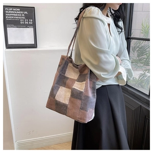 Detailed view of vintage patchwork tote bag in brown canvas worn as a shoulder bag