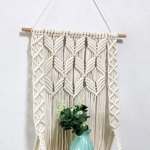 Detail of bohemian handmade cotton rope tapestry with wooden beads on white wall