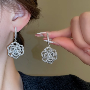 Close-up of silver flower drop earrings with sparkling cubic zirconia and rose petals