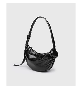 Close-up of black pleated faux leather surface on a crescent shaped shoulder bag