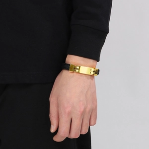 Close-up of men's black braided leather bracelet with a polished gold stainless steel clasp