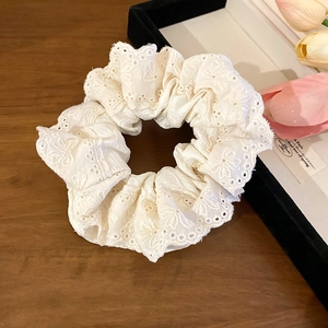 Détail macro du chouchou en dentelle blanc crème avec broderie florale fine