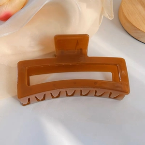 Détail d'une grande pince à cheveux marron caramel sur satin pour coiffures de cheveux épais