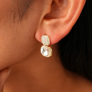 Gros plan d'une boucle d'oreille carrée dorée avec cristal sur lobe de l'oreille