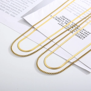 Detail of layered gold titanium steel necklaces showing snake chain and box chain textures