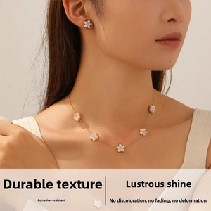 Detail of floral necklace and earrings set with white pearl petals and gold plated finish