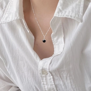 Close-up of minimalist black onyx bead pendant on a fine silver chain worn by a model