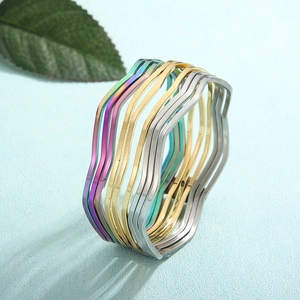 Detailaufnahme gewellter Armreifen in Gold, Silber und Irisierend auf blauem Hintergrund