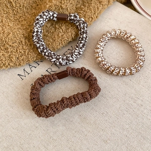 Close-up of woven fabric hair ties and leopard print spiral scrunchies on textured cloth