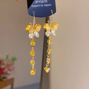 Macro shot of gold butterfly tassel earrings with yellow crystal drops and zircon stones