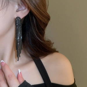 Close-up of elegant black crystal long tassel earrings worn by a fashion model
