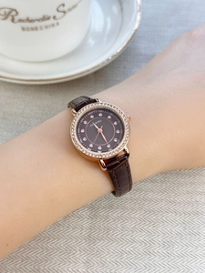 Close-up of luxury women's watch with rose gold diamond bezel and brown leather strap