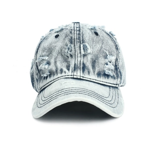 Close-up detail of vintage washed blue denim baseball cap with distressed frayed holes