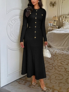 Detail of elegant black knit midi dress showing gold button accents and textured fabric