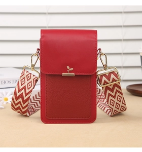 Detail of red leather mini bag with golden leaf clasp and geometric woven shoulder strap