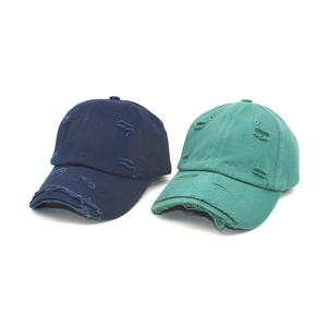 Detail of distressed navy blue and teal baseball caps with vintage frayed edge effects