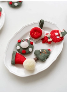 Close-up of handmade felt Christmas ornaments including wreath and tree on a white plate