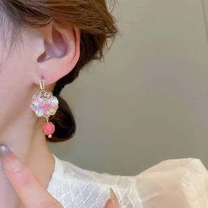 Close-up of pink petal drop earrings with white pearls and beads on a model's ear