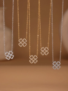 Dettaglio di collane a quadrifoglio con zirconi in finiture argento e oro 18k