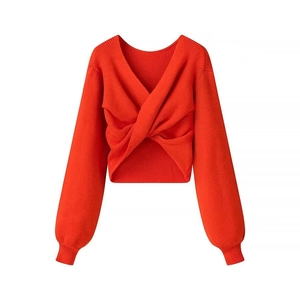 Dettaglio di un maglione corto arancione con scollo a V incrociato e polsini a coste
