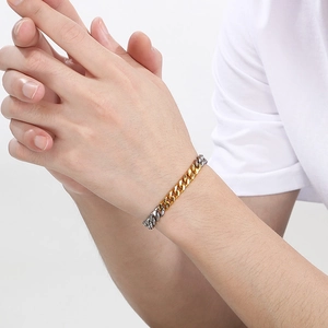 Detailed shot of two-tone gold and silver Cuban chain bracelet worn on a wrist