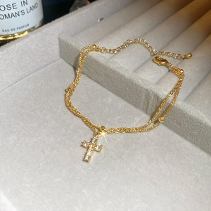 Detail of a gold double-layer cross bracelet with sparkling zircons in a jewelry box