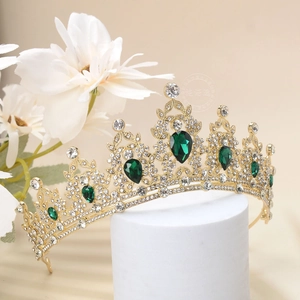 Detail of luxury gold tiara with emerald waterdrop gems and rhinestones for weddings