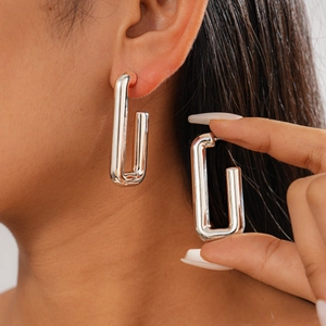 Detailed close-up of rectangular silver hoop earrings with a polished metallic finish