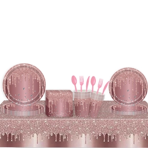 Rose gold party tableware set with plates, cups and cutlery on glittery sequin tablecloth