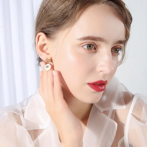 Elegant gold bow earrings with CD shell pendants on model for a sophisticated look
