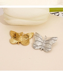 Detailed macro view of butterfly brooches with matte metal texture and crystal accents
