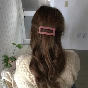 Minimalist matte pink rectangular hair claw clip shown on brunette wavy hair for women