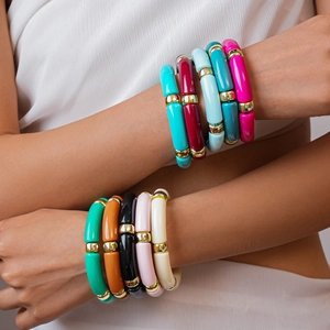 Dettaglio di bracciali colorati in acrilico con perline dorate sul polso di una modella