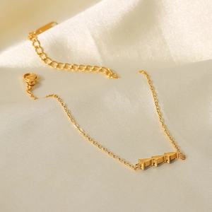 Gros plan d'un bracelet doré 18 carats avec pendentifs oiseaux sur soie