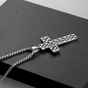 Close-up of silver punk cross pendant with checkerboard pattern and box chain link